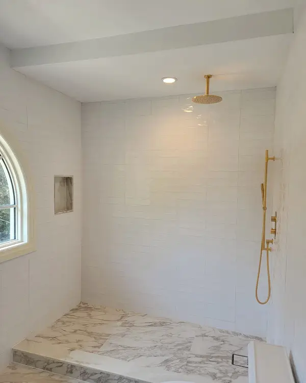 Walk-in shower with gold fixtures and a floor-level entry