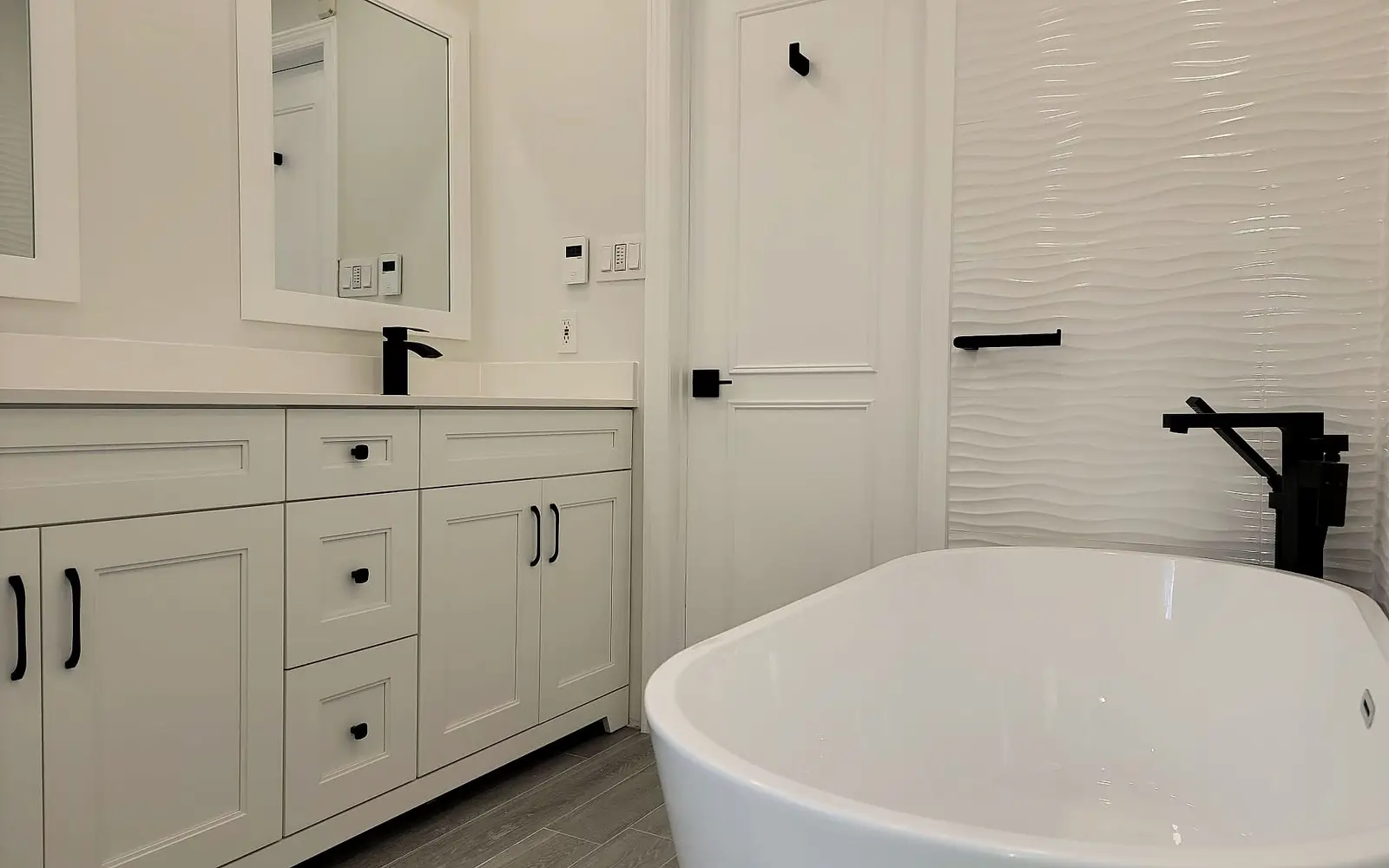 White vanity and freestanding tub with black fixtures