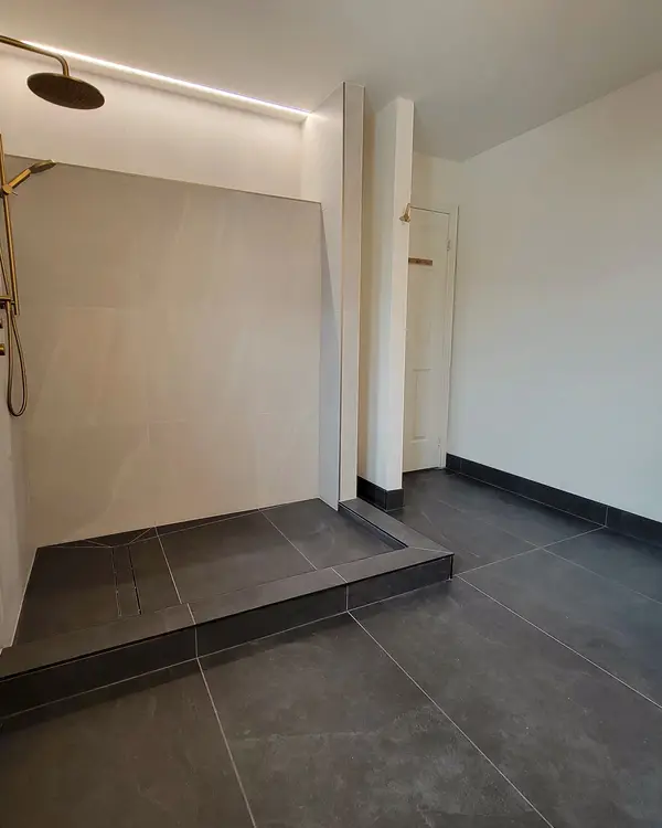 Large-format charcoal floor tile running into a curbless shower