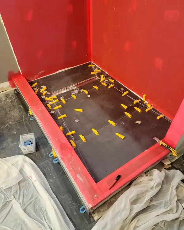 Red waterproofing membrane on the shower walls and floor before tile