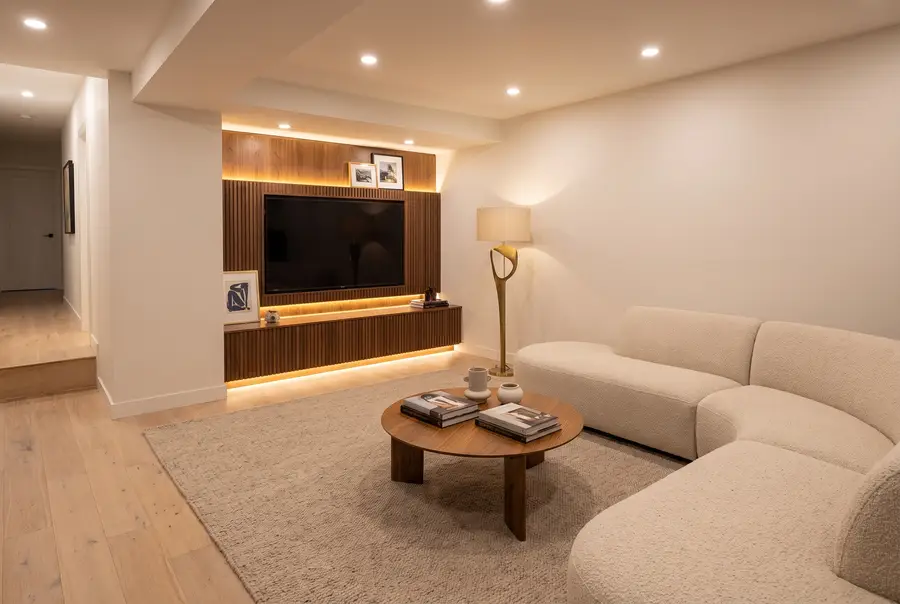 Finished basement family room with a fluted walnut media wall and ivory sectional