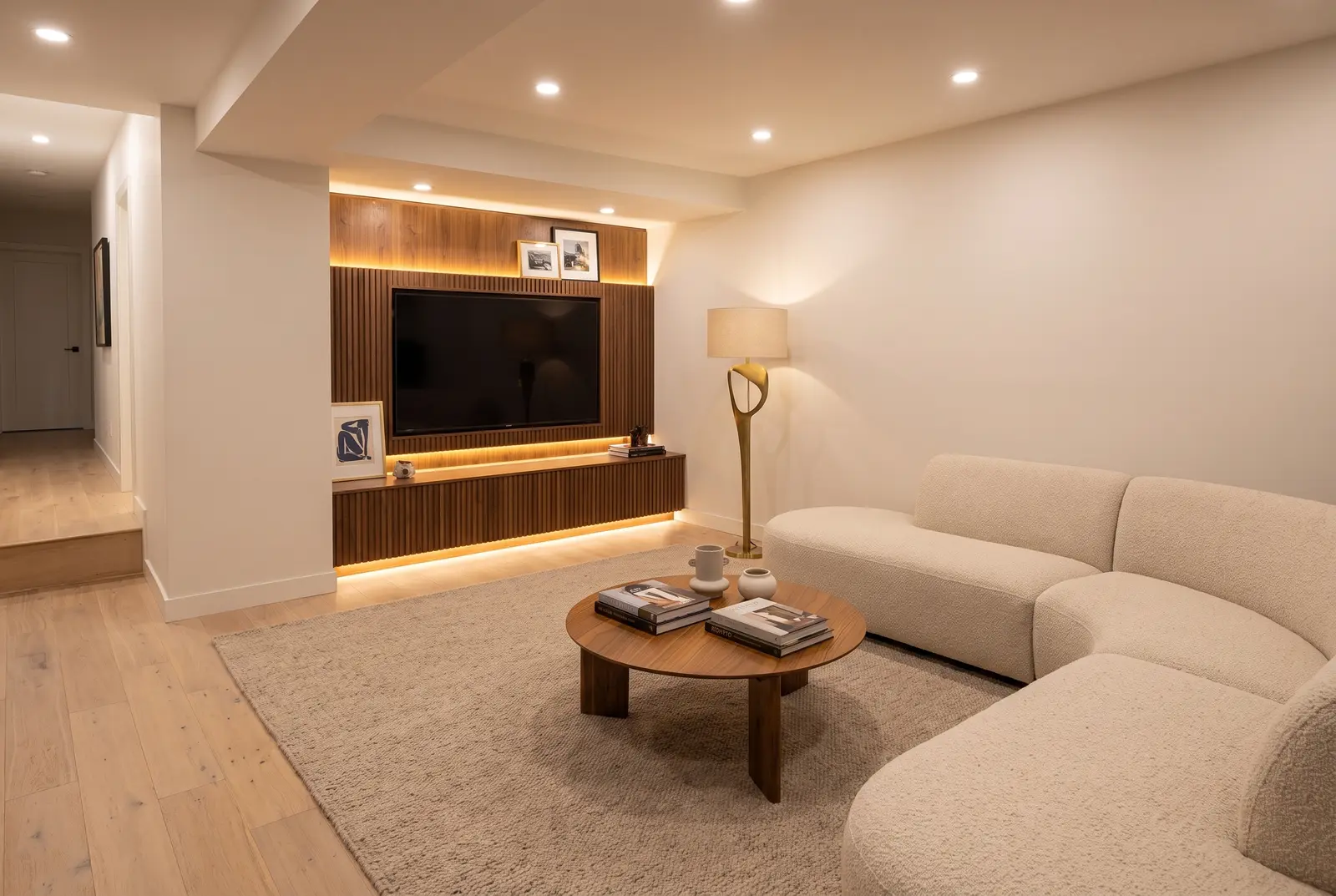 Finished basement family room with a fluted walnut media wall and ivory sectional